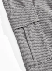 Close-up detail of grey corduroy fabric texture and pocket flap on men's cargo pants