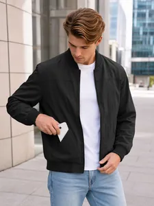 Close-up of a man putting a white smartphone in the side pocket of a black bomber jacket