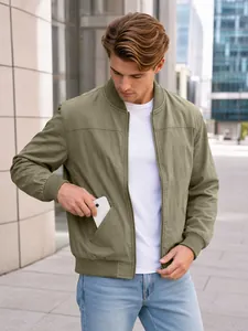 Close-up of a man putting a smartphone into the side pocket of an olive green bomber jacket.