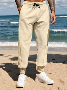 Detailed view of men's beige joggers in a relaxed fit with cuffed ankles.