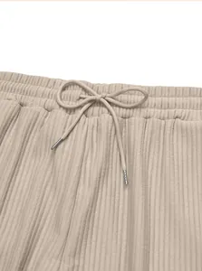 Close-up detail of beige ribbed trousers showing elastic waistband and drawstring bow