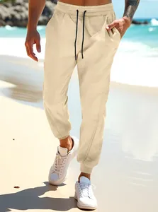 Men's casual beige joggers with drawstring waist and cuffed ankles at the beach