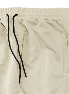 Macro view showing the elastic waistband and black drawstrings on beige men's casual pants