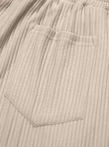Close-up detail of the ribbed fabric and pocket stitching on beige casual trousers.