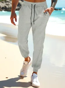 Close-up view of men's grey casual drawstring joggers in a sunny beach setting