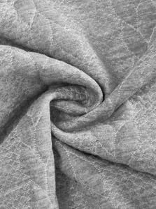 Dettaglio macro del morbido tessuto a maglia jacquard grigio per maglione invernale.