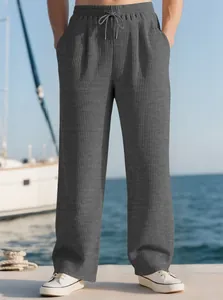 Detailed view of men's grey ribbed straight casual trousers in a seaside setting