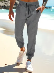Stylish men's heather gray casual joggers featuring drawstring waist and elastic cuffs on a beach.