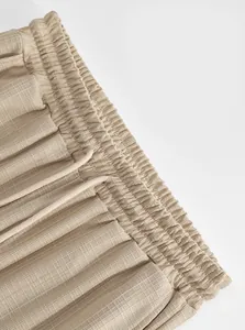 Detail view of the elastic waistband and drawstring on textured khaki cargo pants