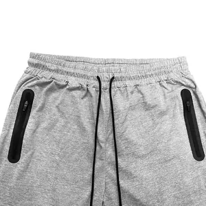 Detail view of men's gray joggers featuring elastic waist and black zipper pockets.