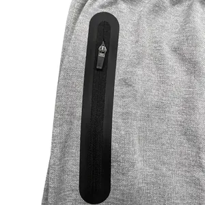 Close-up detail of the vertical zippered pocket on these gray athletic jogger pants