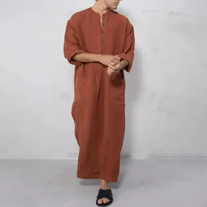 Gros plan d'un homme portant un caftan ample rouille avec col montant et poches avant