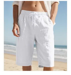 Close-up detail of white cotton linen drawstring beach shorts worn by a model at the seaside
