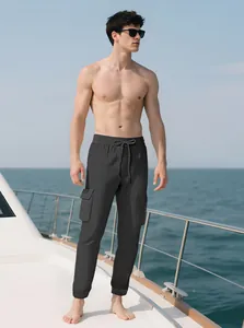 Lifestyle shot of a man wearing slim fit dark grey cargo joggers on a sunlit yacht deck