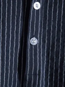 Detail shot of navy striped shirt showing fine fabric texture and translucent buttons