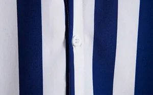 Detailgetreue Nahaufnahme eines blau-weiß gestreiften Hemdstoffes mit weißem Knopf.
