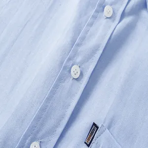 Detalle de cerca de una camisa Oxford azul claro con botones blancos y costuras limpias