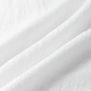 Macro shot showing the breathable white cotton fabric texture of the men's shirt set.