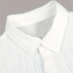 Gros plan sur la texture du tissu et le détail du col de la chemise blanche