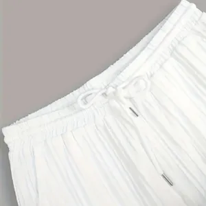 Gros plan sur la taille élastique et le cordon de serrage d'un pantalon plissé blanc