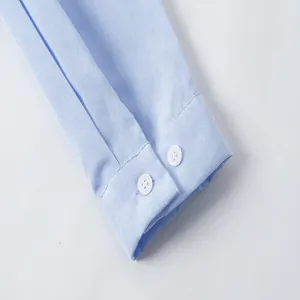 Primer plano detallado del puño de una camisa Oxford azul claro con botones blancos