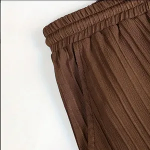 Gros plan sur la texture du tissu plissé marron et la taille élastique d'un pantalon