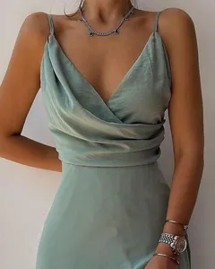 Gros plan d'une robe élégante en satin vert avec col en V, taille plissée et fines bretelles.