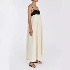 Elegant two-tone color-block maxi dress with thin straps and cream-colored flowing skirt.