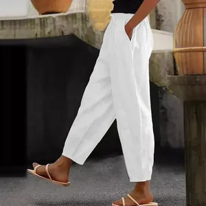 Side view of white cotton linen trousers featuring elastic waist and side pockets.