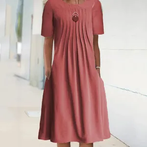 Detailed view of women's short sleeve pleated midi dress featuring pockets and round neck.