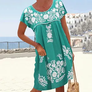 Detail of turquoise ethnic dress featuring white floral embroidery and round neckline
