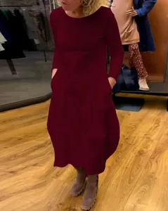 Ganzkörperansicht eines weinroten Langarmkleides an einer Person mit Seitentaschen im Shop