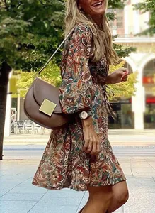 Stylish woman wearing a vintage paisley print long balloon sleeve mini dress in city street