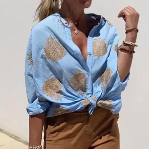 Detailansicht der hellblauen Damenbluse mit goldenen ethnischen Stickereien und Knöpfen