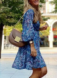 Woman wearing a blue paisley print floral mini dress in a lifestyle street setting