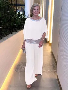 Elegant white two-piece set featuring sequin trim batwing top and wide-leg trousers.