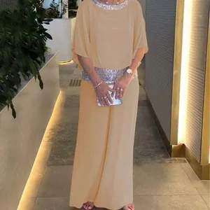 Ensemble élégant champagne avec haut chauve-souris à paillettes et pantalon large.