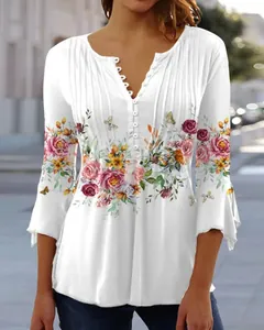 Close-up of elegant floral print and pleated detail on a white V-neck women's top