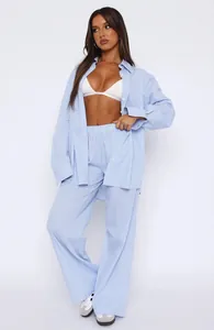 Full body view of a woman wearing a blue striped oversized shirt and wide-leg trousers set