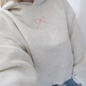 Übergroßer melierter grauer Baumwoll-Hoodie mit feiner rosa Schleifenstickerei vorne