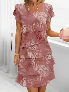 Detail of pink layered chiffon dress with white 3D floral print and short sleeves.