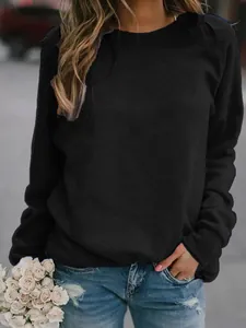 Detailed view of a woman wearing a minimalist black long-sleeve crewneck sweatshirt.