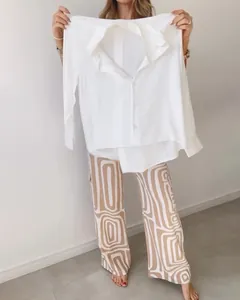 Detail view of a white casual shirt and printed wide-leg pants set held by model