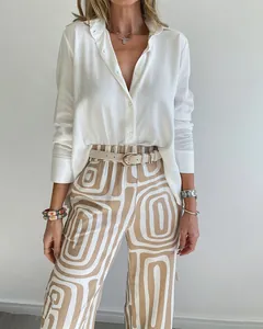 Close-up detail of woman in white shirt and geometric print trousers with belt