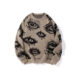 Detailed view of beige knitted sweater featuring bold black jacquard eye patterns
