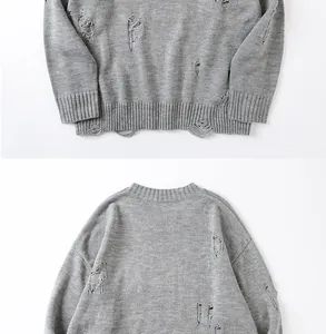 Dettaglio del maglione grigio a girocollo con fori ed effetto strappato di tendenza