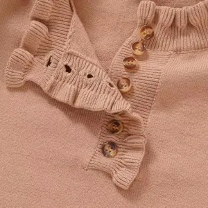 Close-up view of a pink knit sweater with elegant ruffle collar and brown button details