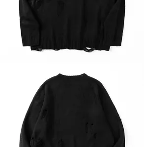 Dettaglio di un maglione nero in maglia con strappi e bordo a costine stile grunge