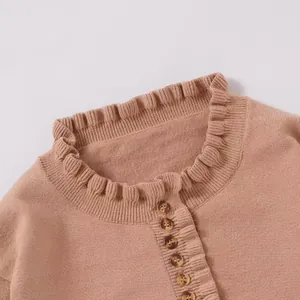 Detailed close-up showing the elegant ruffled collar and button trim on pink knit sweater