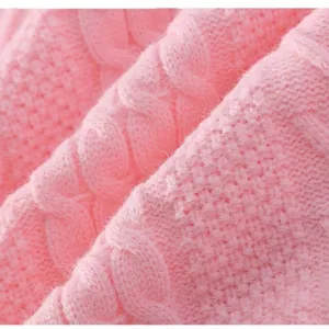 Macro detail of a high-quality pink cable knit sweater showing intricate weaving pattern